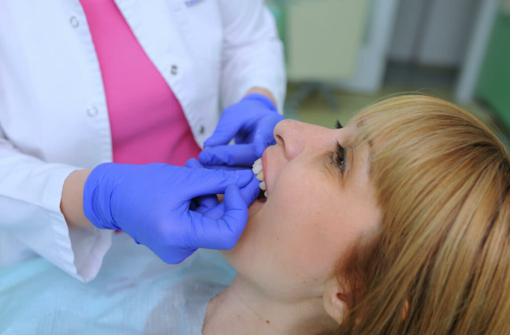 Dentist putting on veneers on her patient's teeth.