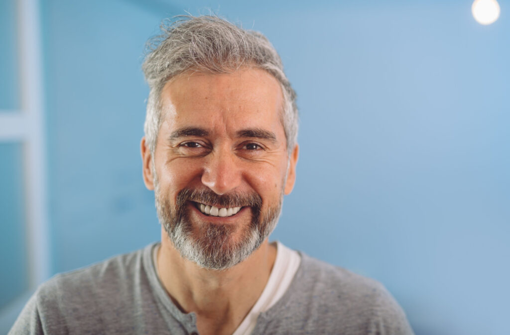 A man with gray hair and beard smiling and looking directly at the camera