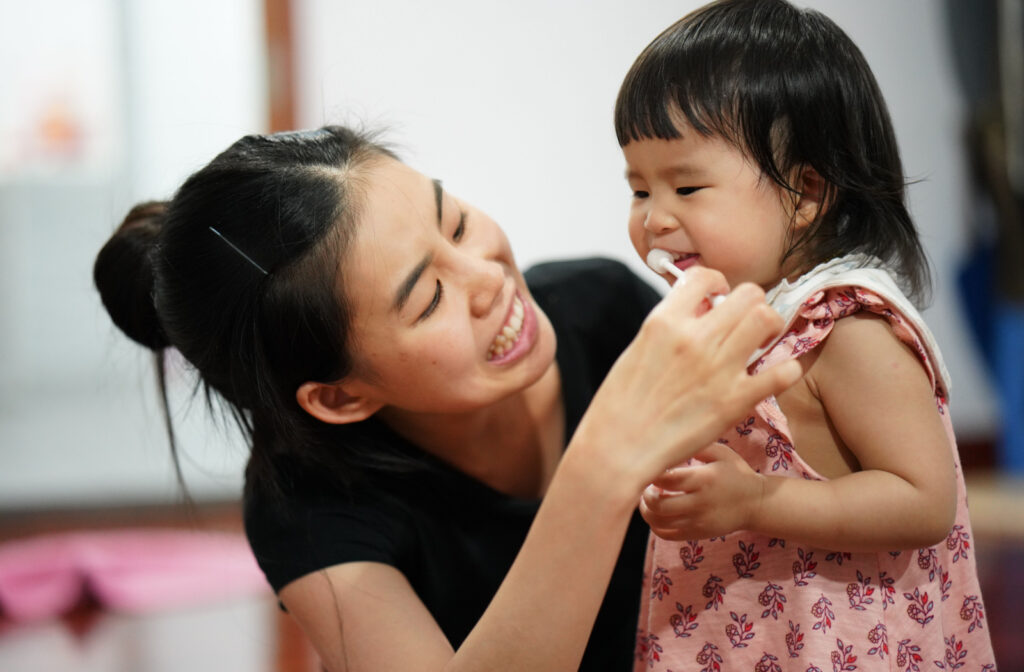 A woman brushing the teeth of her child.