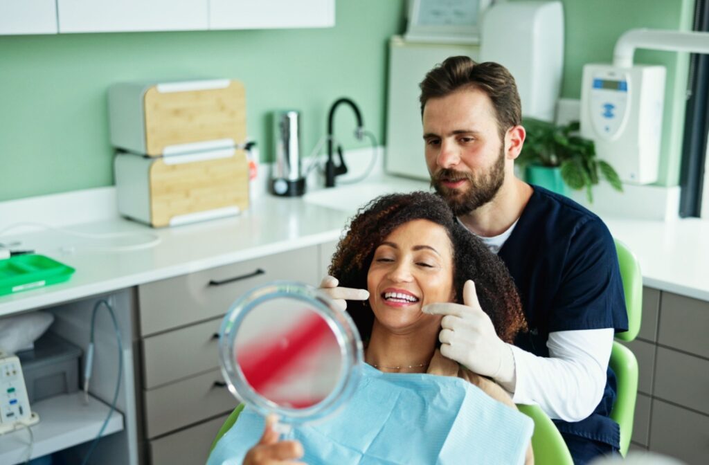 A dental professional showing a patient their smile in a mirror discussing results in a modern clinic setting