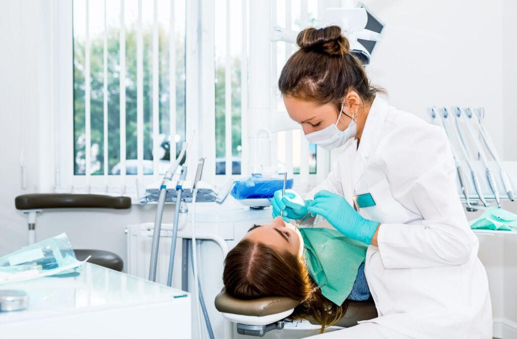 A dentist performs an oral examination during their patient's recall exam appointment.