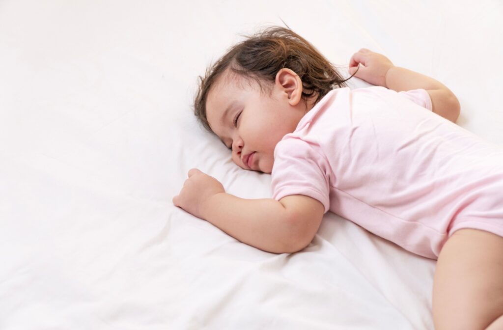 Toddler sleeping on their side on white sheets.