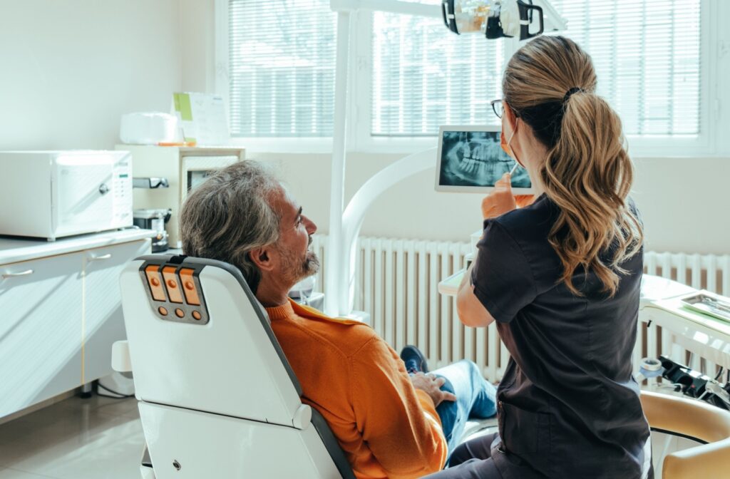 A dental assistance examining a patients teeth x-rays with them