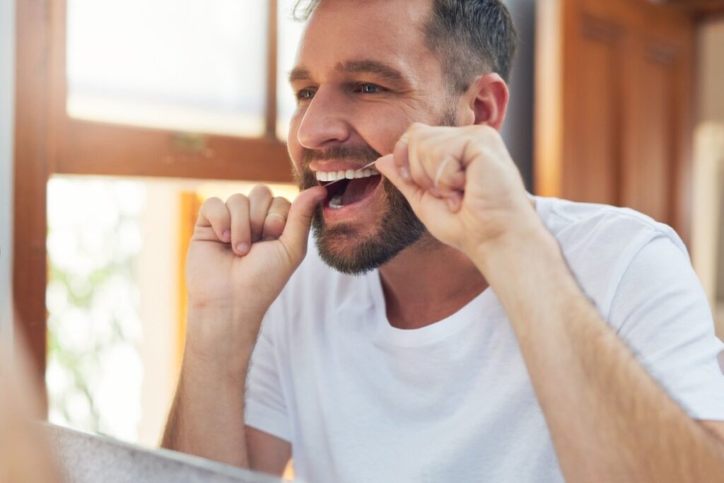 A person flossing their teeth in the mirror